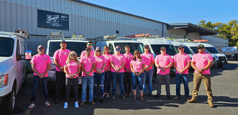 The staff of Greg's HVAC in front of their shop and fleet of vehicles.